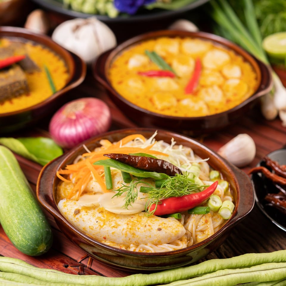 Three bowls of Chinese curry dishes with noodles, fish cakes, vegetables, and chili peppers.