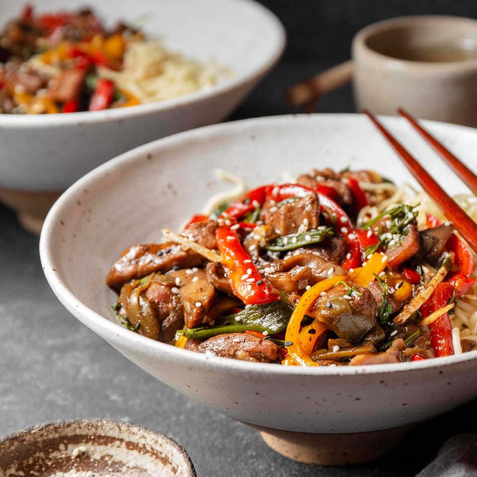 Two bowls of China House's beef and vegetable stir-fry with noodles, garnished with sesame seeds.