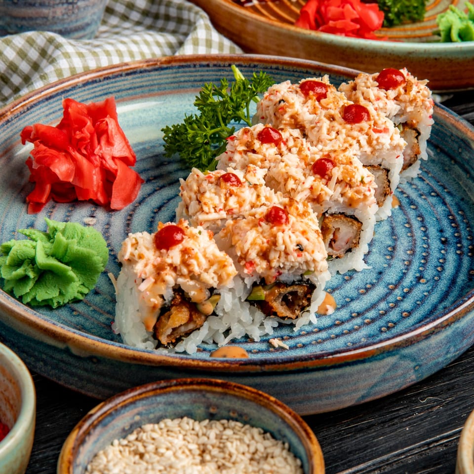 China House's sushi rolls with crab topping, red sauce, pickled ginger, and wasabi on a blue plate.
